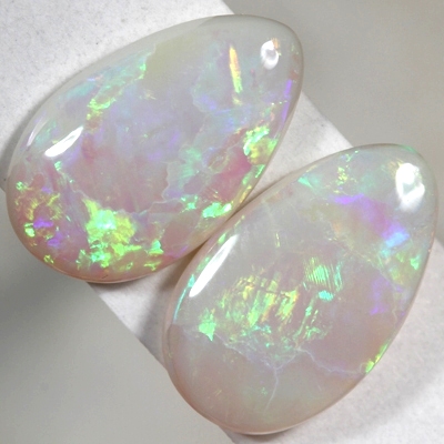 SOLID SEMI BLACK OPALS Matching pair. bright green and orange rolling flashes over a hue of purple